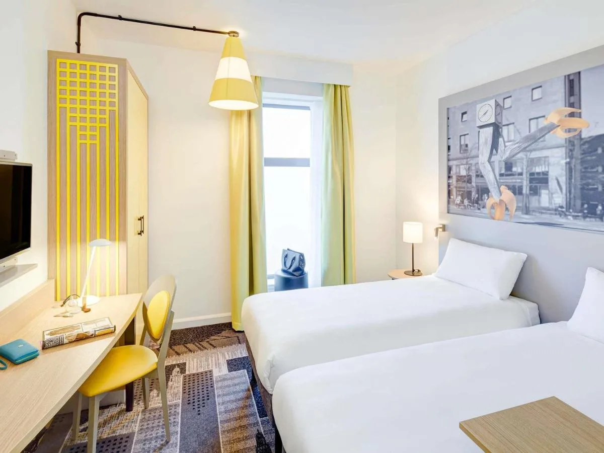 a hotel room with two beds and a desk at ibis Styles Glasgow Centre George Square in Glasgow