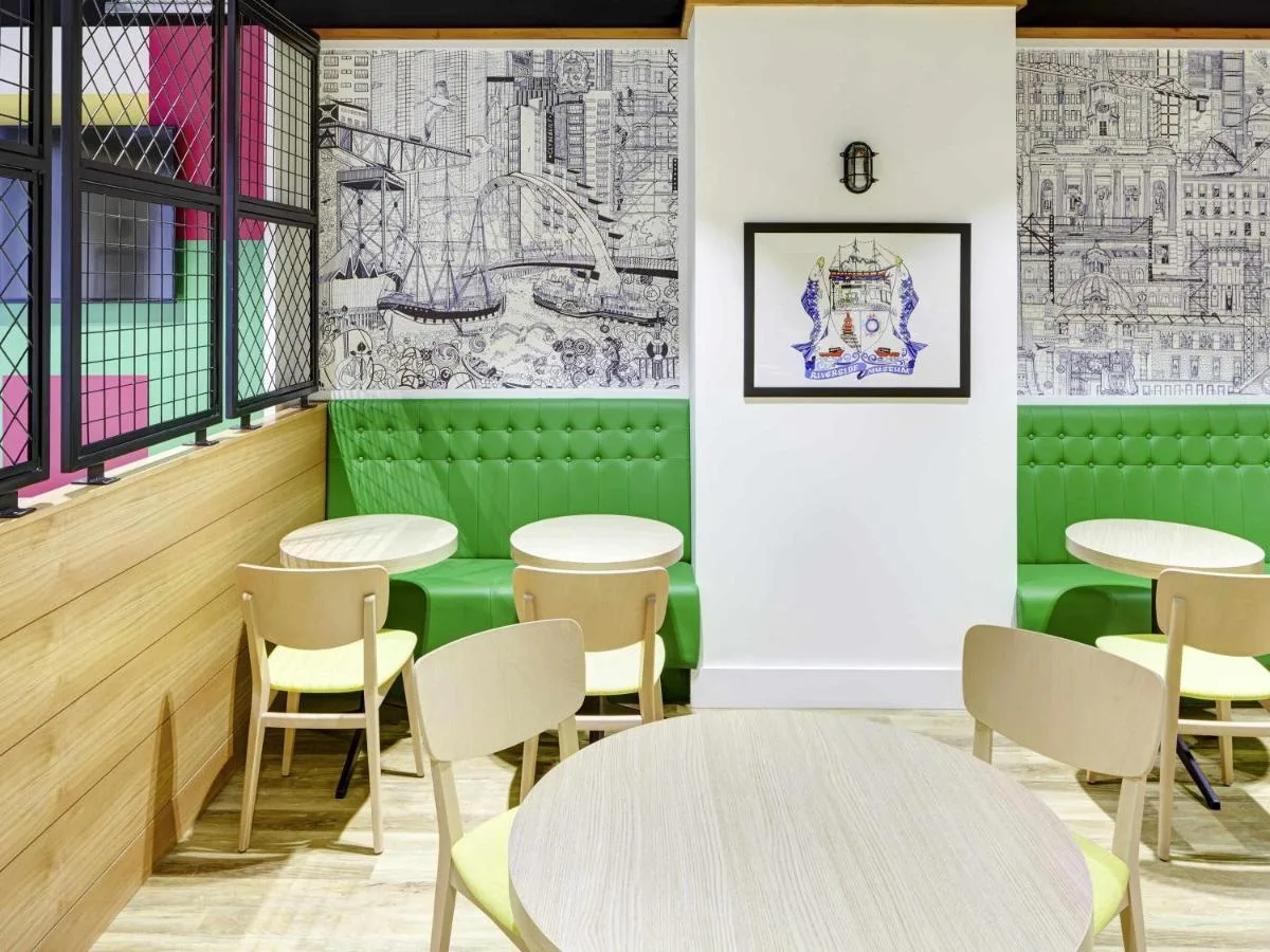a restaurant with green walls and tables and chairs at ibis Styles Glasgow Centre George Square in Glasgow